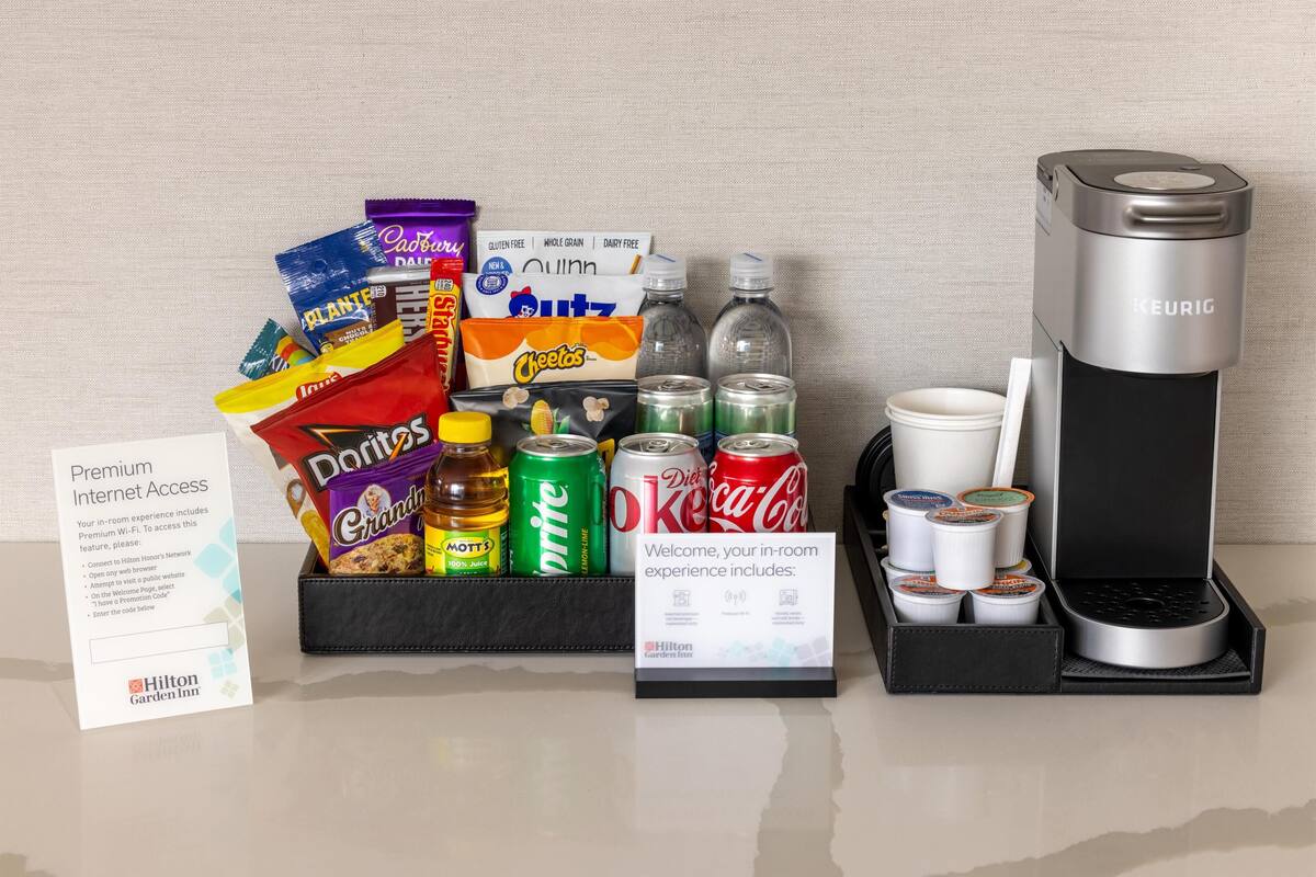 A minibar setup with snacks, drinks, and a Keurig coffee maker.