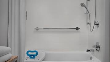 A bathroom with a bathtub, a showerhead, a grab bar, and a towel rack.