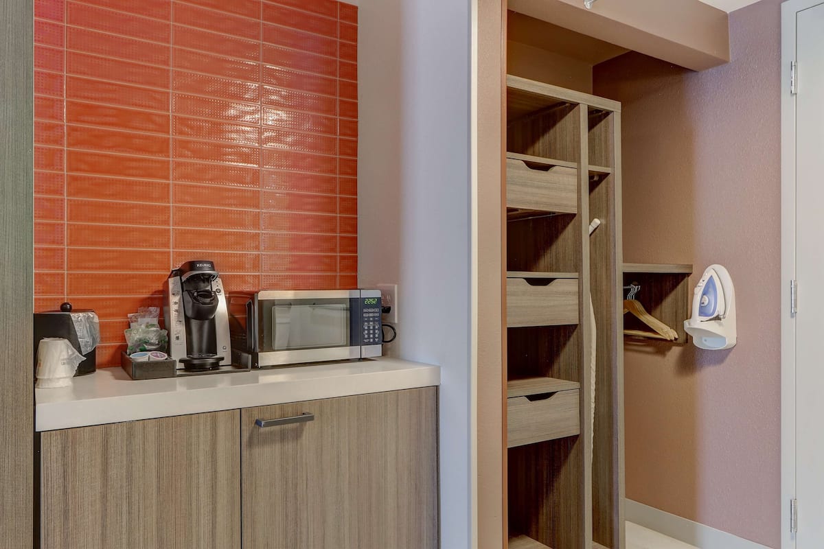 A kitchenette with a microwave, coffee maker, and storage cabinets.