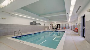 An indoor swimming pool with clear lane markings, a tiled floor, and a ceiling with recessed lighting.