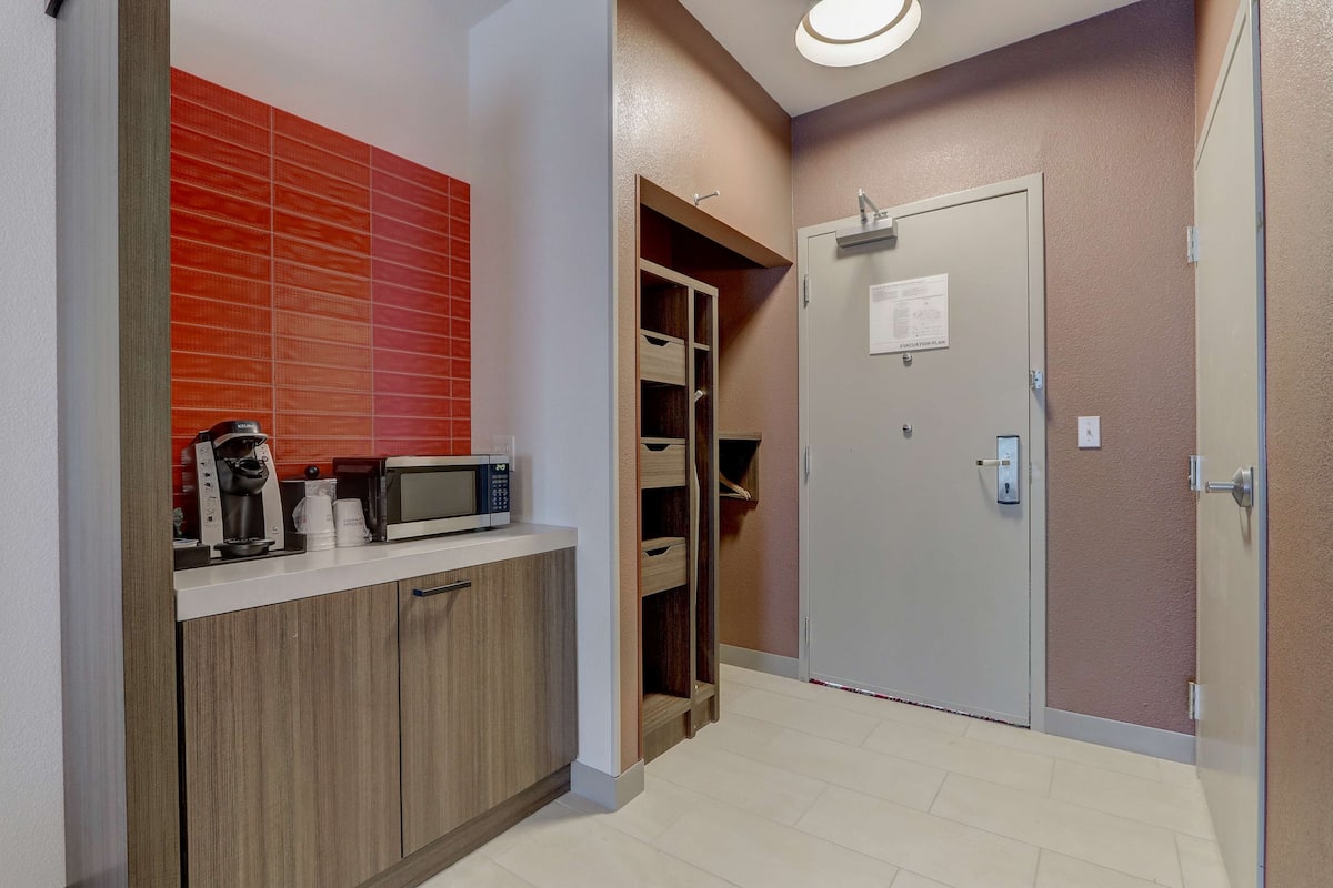 A modern kitchen with a microwave, coffee maker, and cabinets.