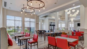 A spacious dining area with high ceilings, modern pendant lighting, and large windows offering views of the outdoors.