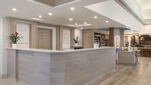 A modern reception area with a central counter, a bar, and a seating area.