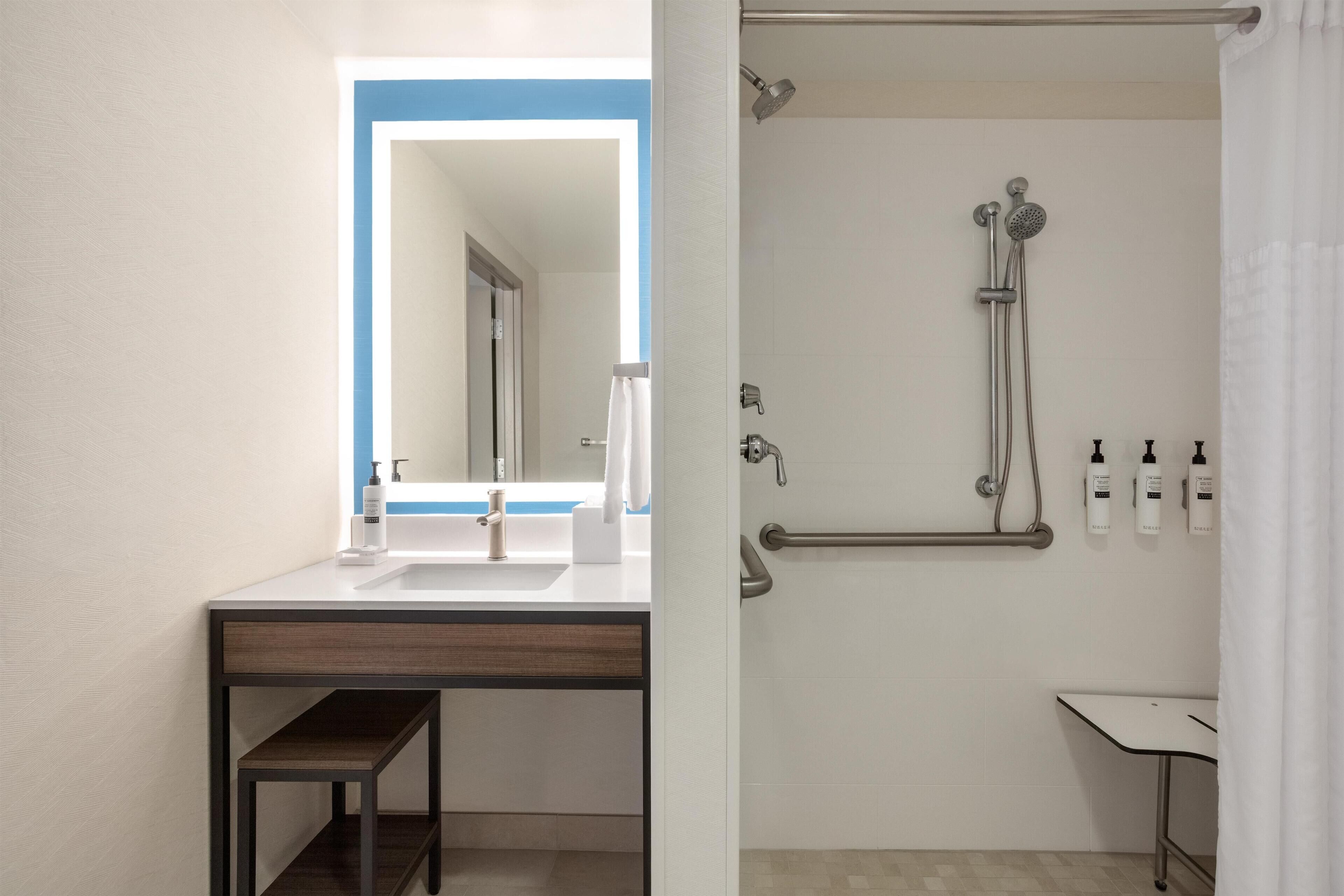 A modern bathroom with a sink, mirror, and shower.