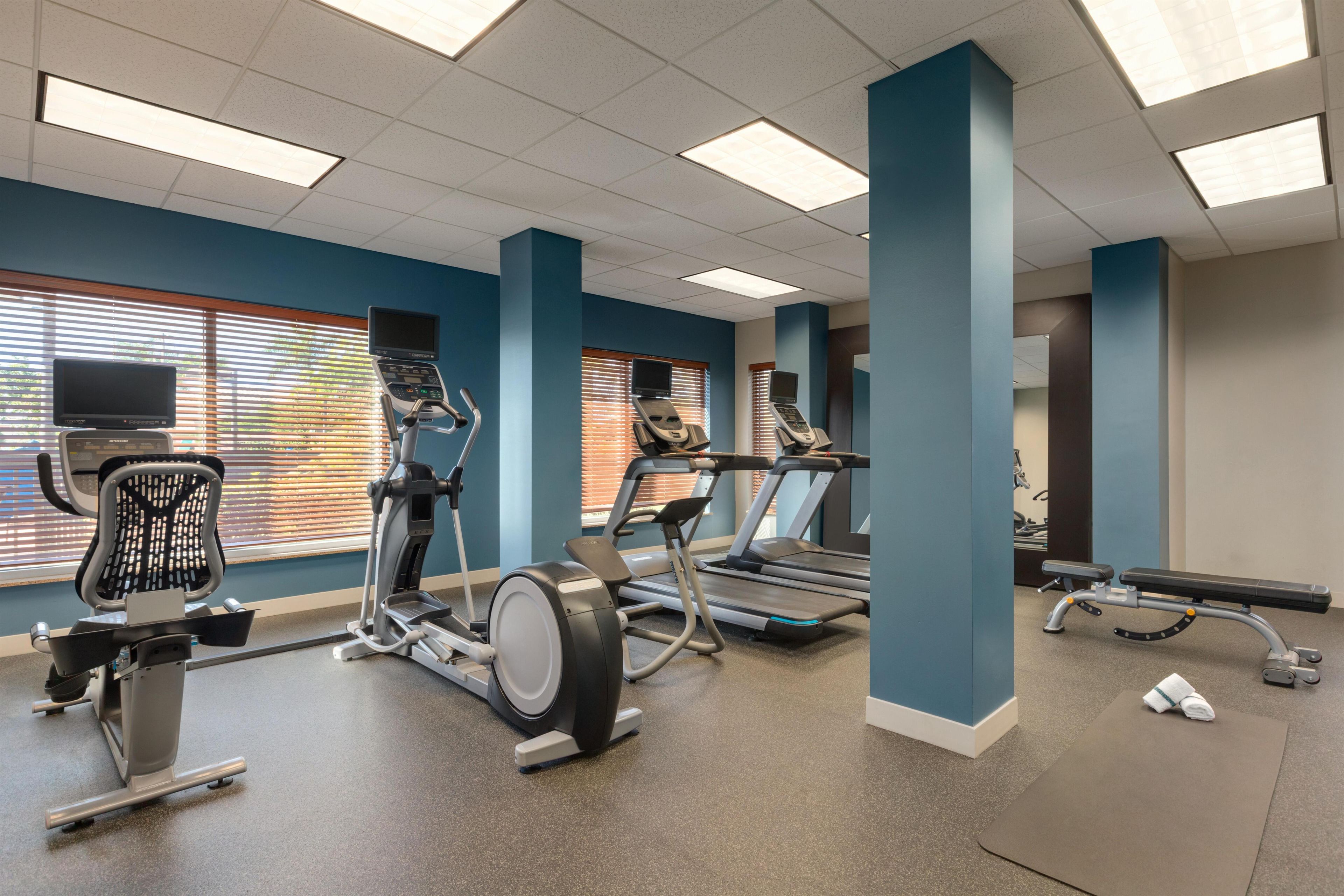 Ein Fitnessstudio mit Laufbändern, einem Crosstrainer und einem Ergometer.