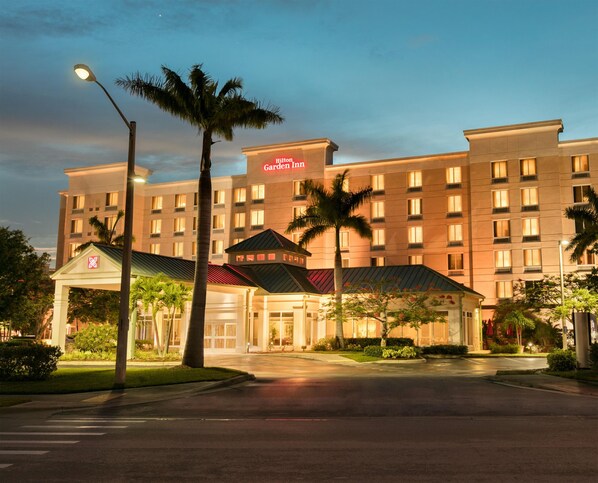 Un hotel de varios pisos con un cartel llamativo, entrada cubierta y un camino de acceso bien iluminado.