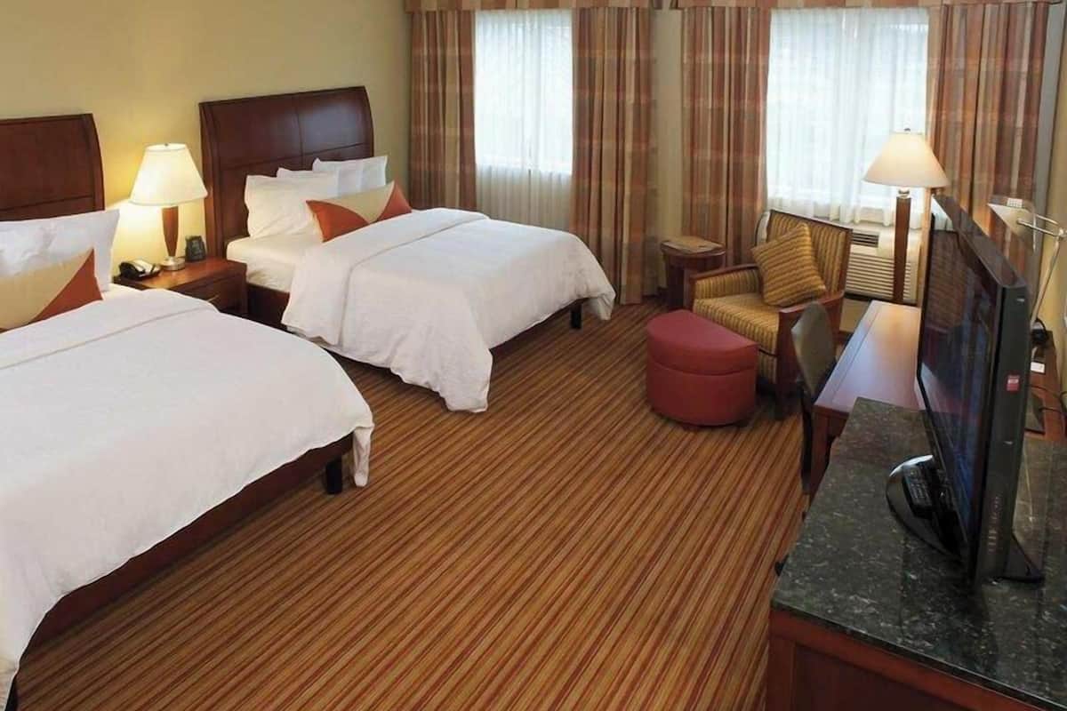 Een hotelkamer met twee bedden, een televisie, een bureau en een stoel.