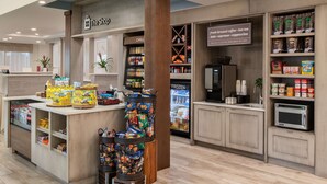 A coffee shop with a 'The Shop' sign, a refrigerated section, and a variety of snacks and beverages.