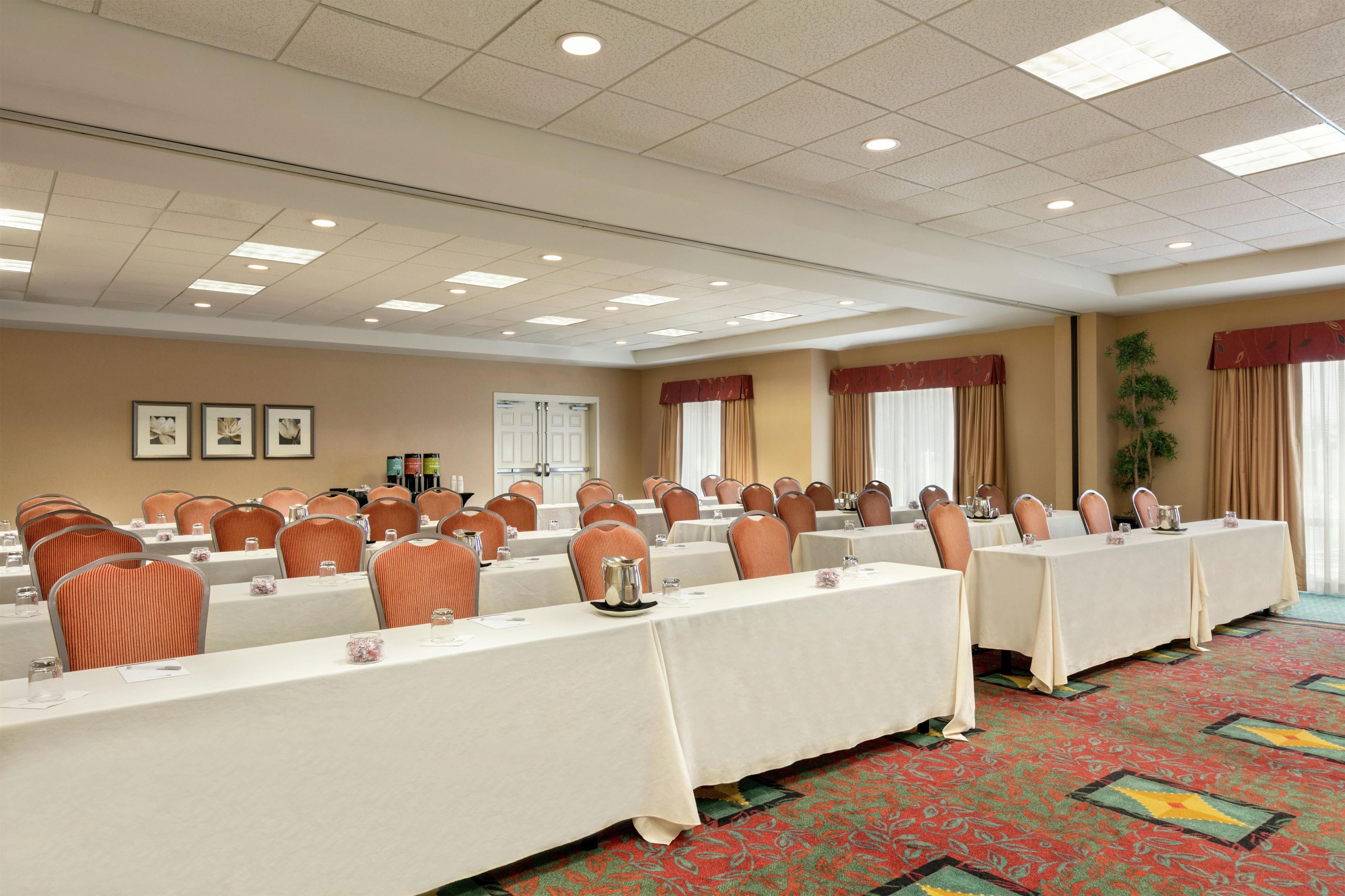A conference room with long tables, chairs, and a carpeted floor.