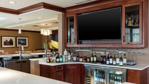 A bar area with a wine and liquor display, a large flat-screen TV, and a refrigerator.