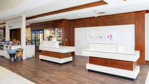 A hotel lobby with reception desks, a minibar, and a food service area.