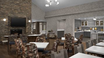 A modern hotel lobby with a stone wall, a flat-screen TV, a fireplace, and a dining area with patterned chairs and tables.