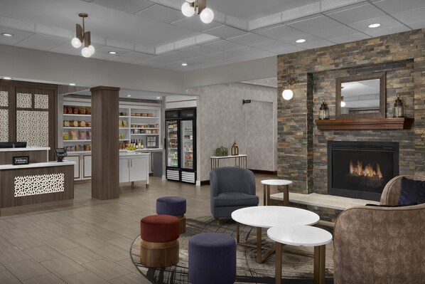 Un moderno vestíbulo de hotel con chimenea, zona de estar y kitchenette.