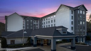 A hotel with a modern design, a covered entrance, and a sign indicating it is a Hampton Inn by Hilton.