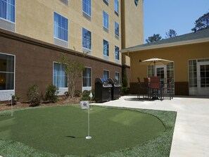 A courtyard with artificial turf, a barbecue grill, and outdoor seating.