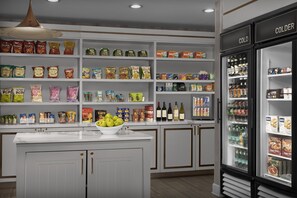 Interior de un supermercado con estantes llenos de aperitivos, bebidas y una sección refrigerada.