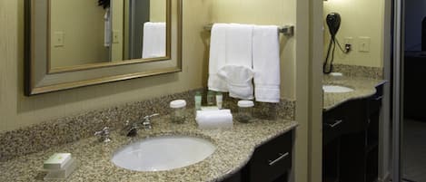 Une salle de bain d’hôtel avec deux lavabos, un grand miroir et un sèche-cheveux fixé au mur.