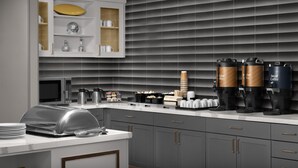 A modern kitchen with a built-in microwave, coffee machines, and a glass-top buffet.