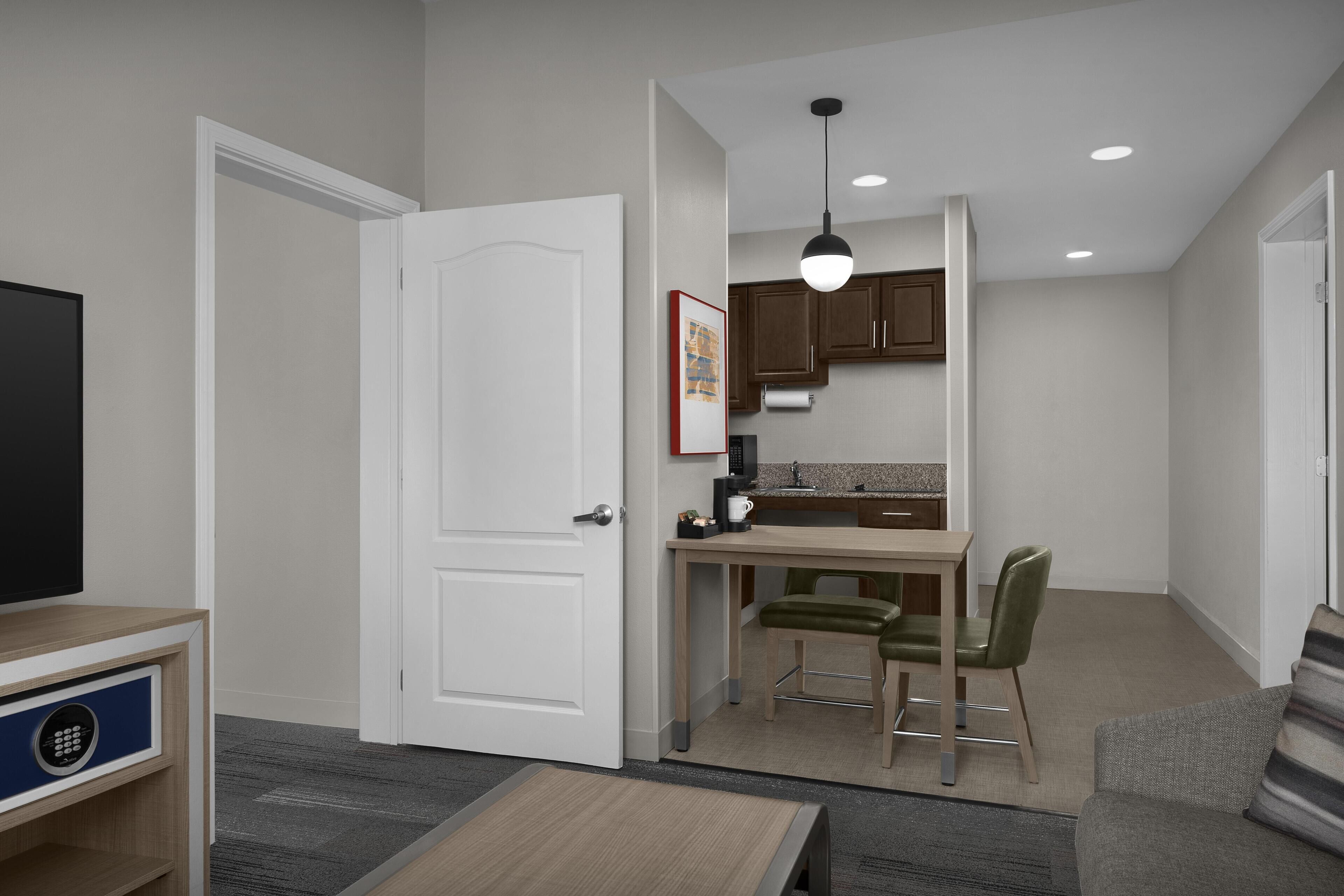 A compact living space with a kitchenette, a dining area, a TV, and a sofa.