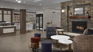 A hotel lobby with a fireplace, seating area, and a kitchenette.