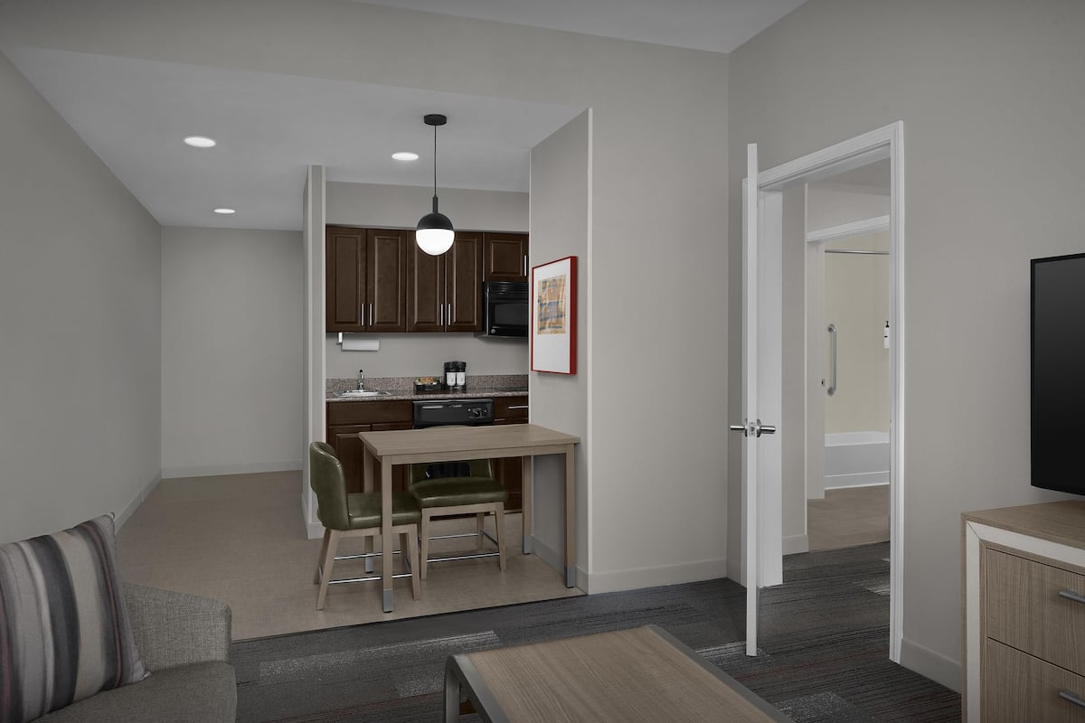 A compact living space with a kitchenette, a dining area, a sofa, and a TV.
