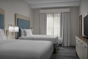 A hotel room with two beds, a large window with curtains, a flat-screen TV, and a minibar.
