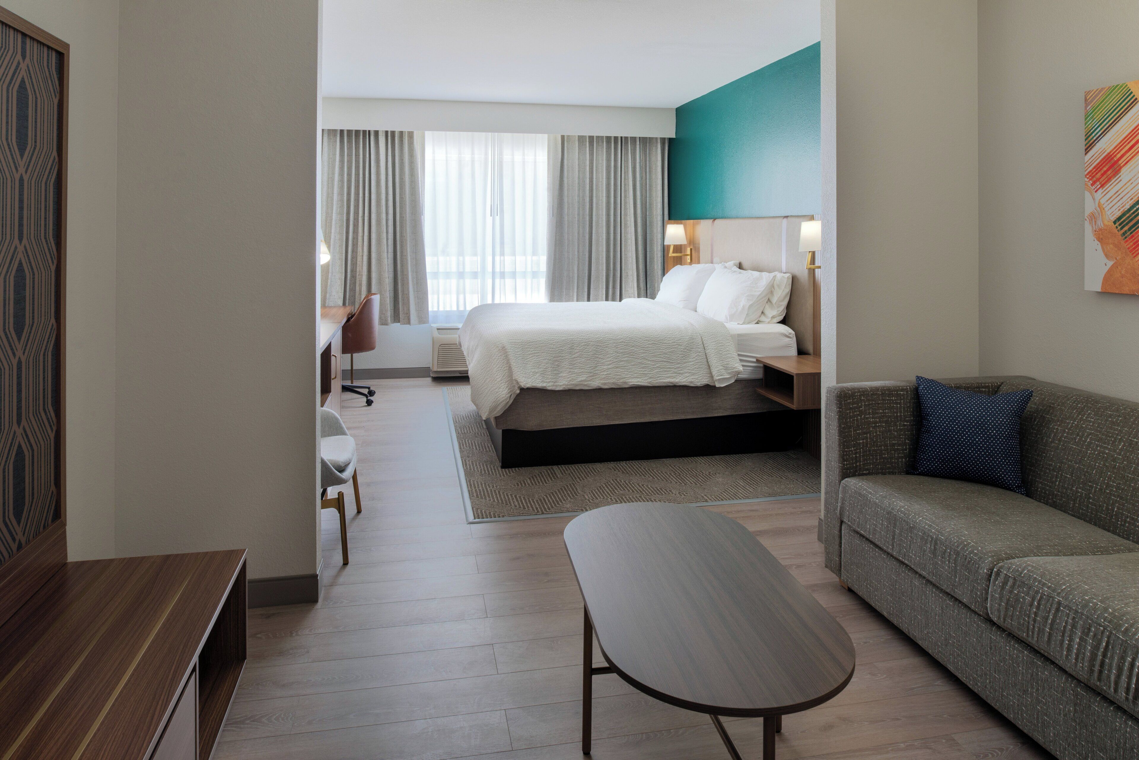 Et hotelværelse med en seng, en sofa, et skrivebord og en stol.