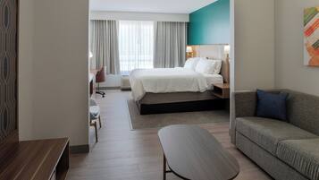 Et hotelværelse med en seng, en sofa, et skrivebord og en stol.