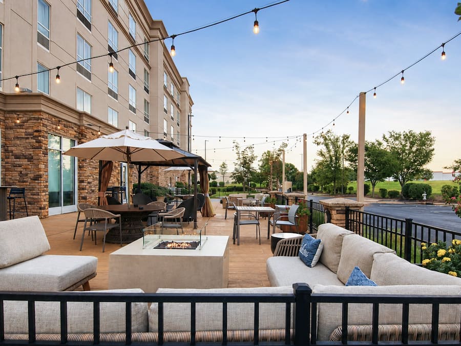 An outdoor patio with seating, a fire pit, and string lights.