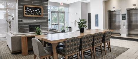 A modern conference room with a long table, chairs, a fireplace, and an exit sign.