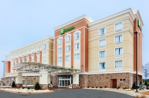 Um hotel Holiday Inn Express com fachada moderna, entrada coberta e estacionamento.