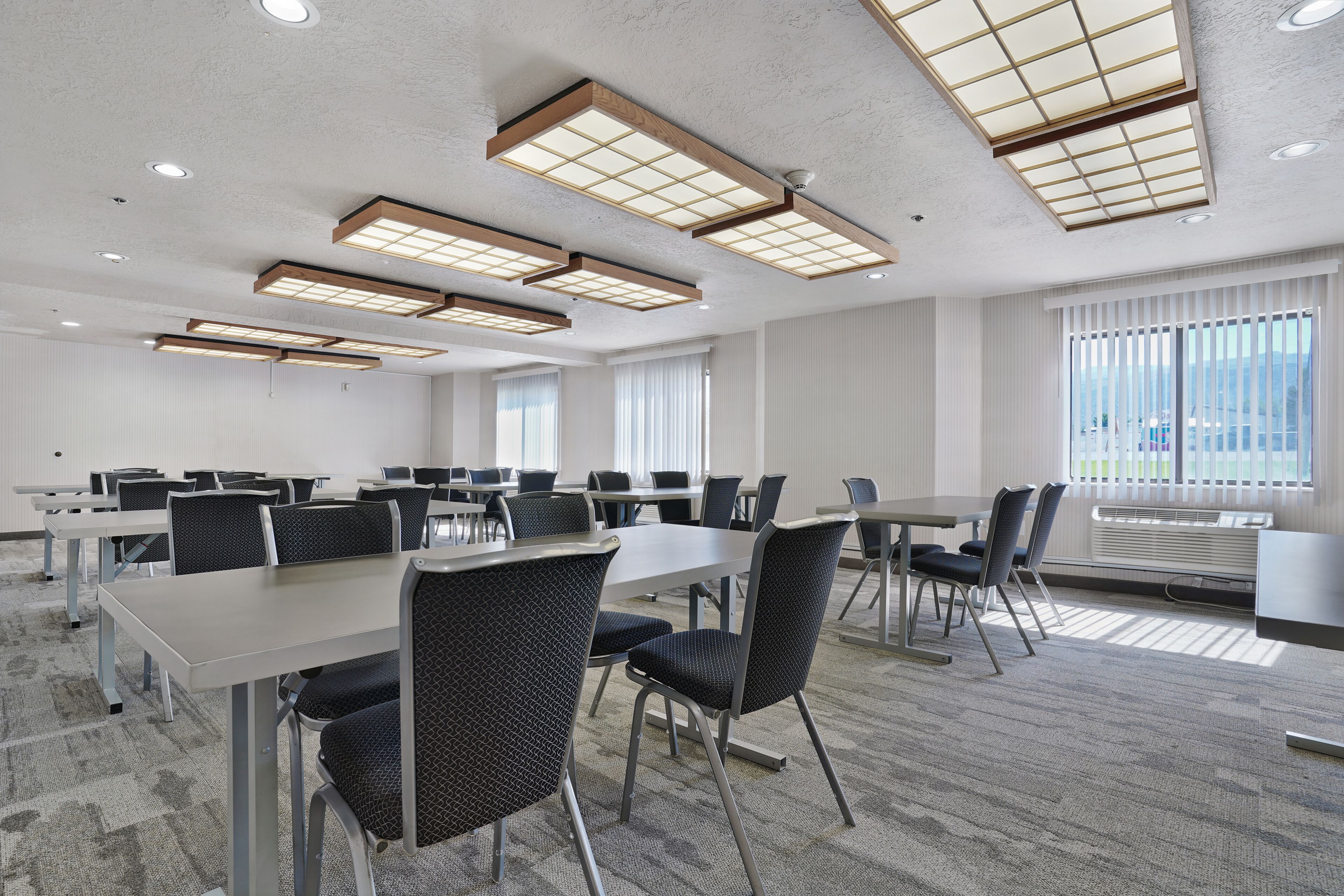 A conference room with tables, chairs, and recessed ceiling lights.