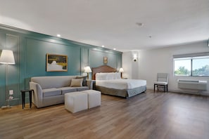 A modern hotel room with a bed, a sofa, a chair, and a small table. - Willow Creek Inn (Ephraim)