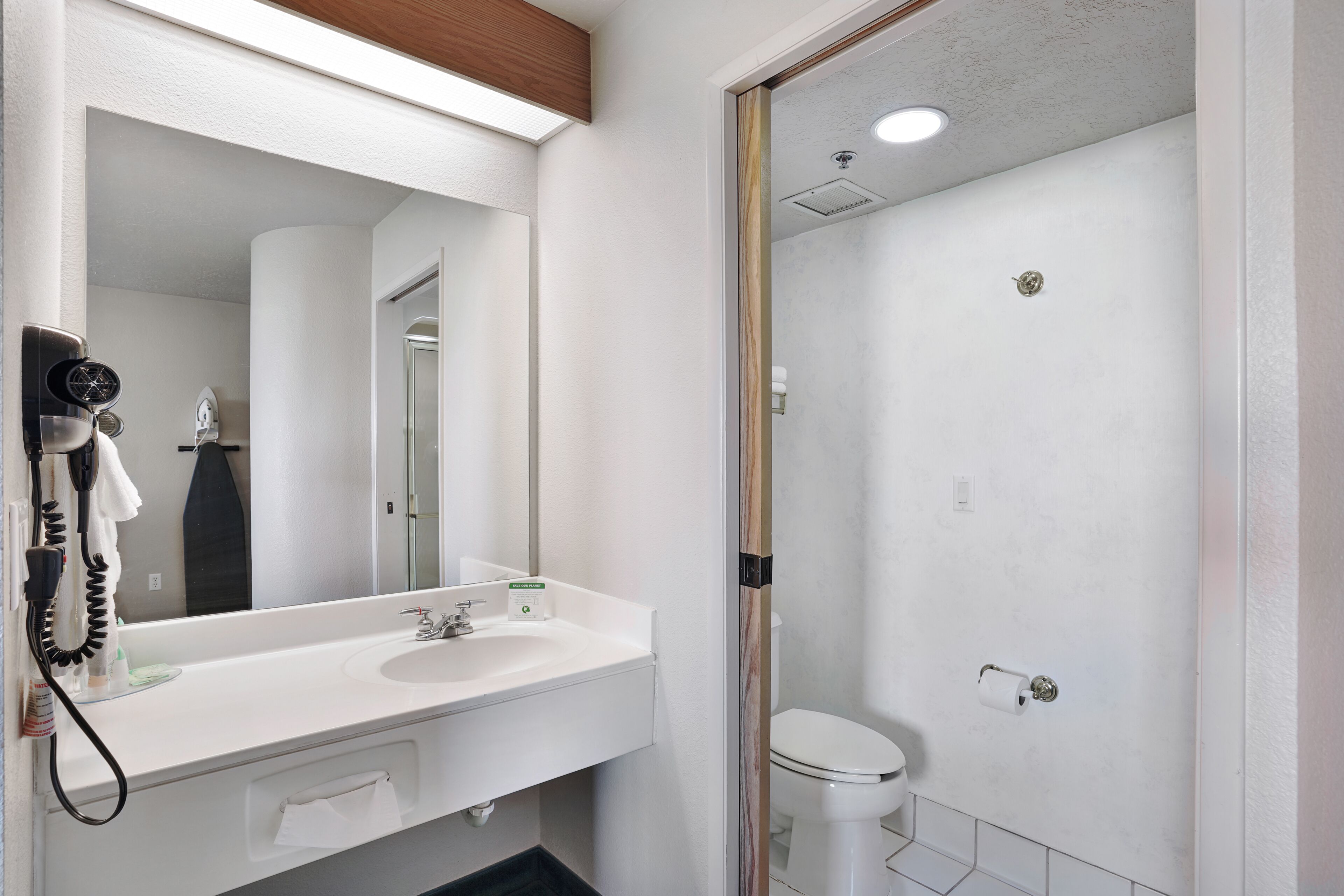 Een badkamer met een witte wastafel, spiegel en toilet.