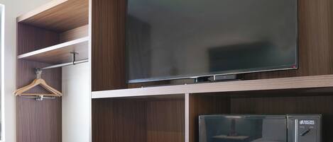 A modern kitchen with a microwave, wooden cabinets, and a hanging clothes rack.
