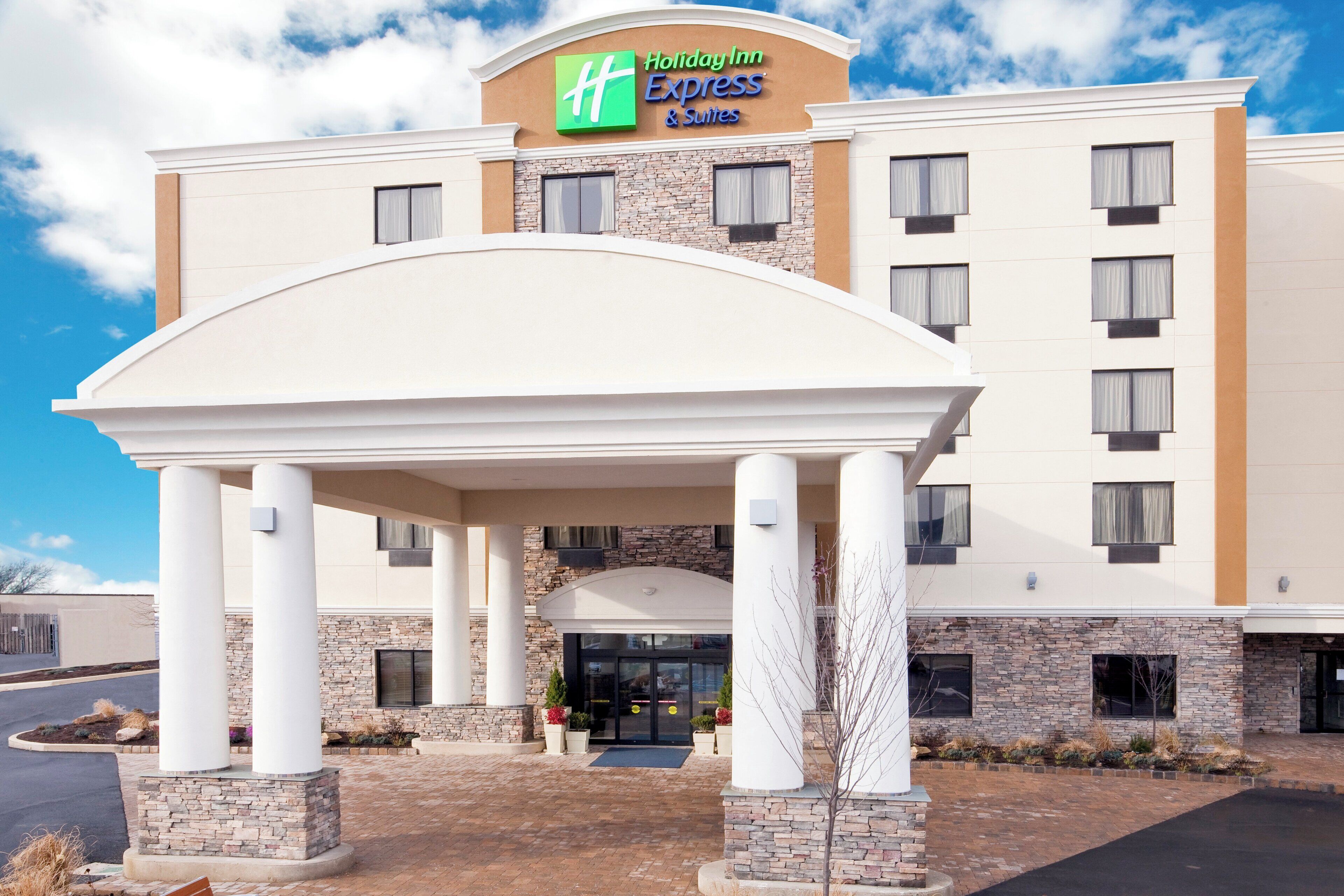 A Holiday Inn Express & Suites building with a covered entrance and stone facade.