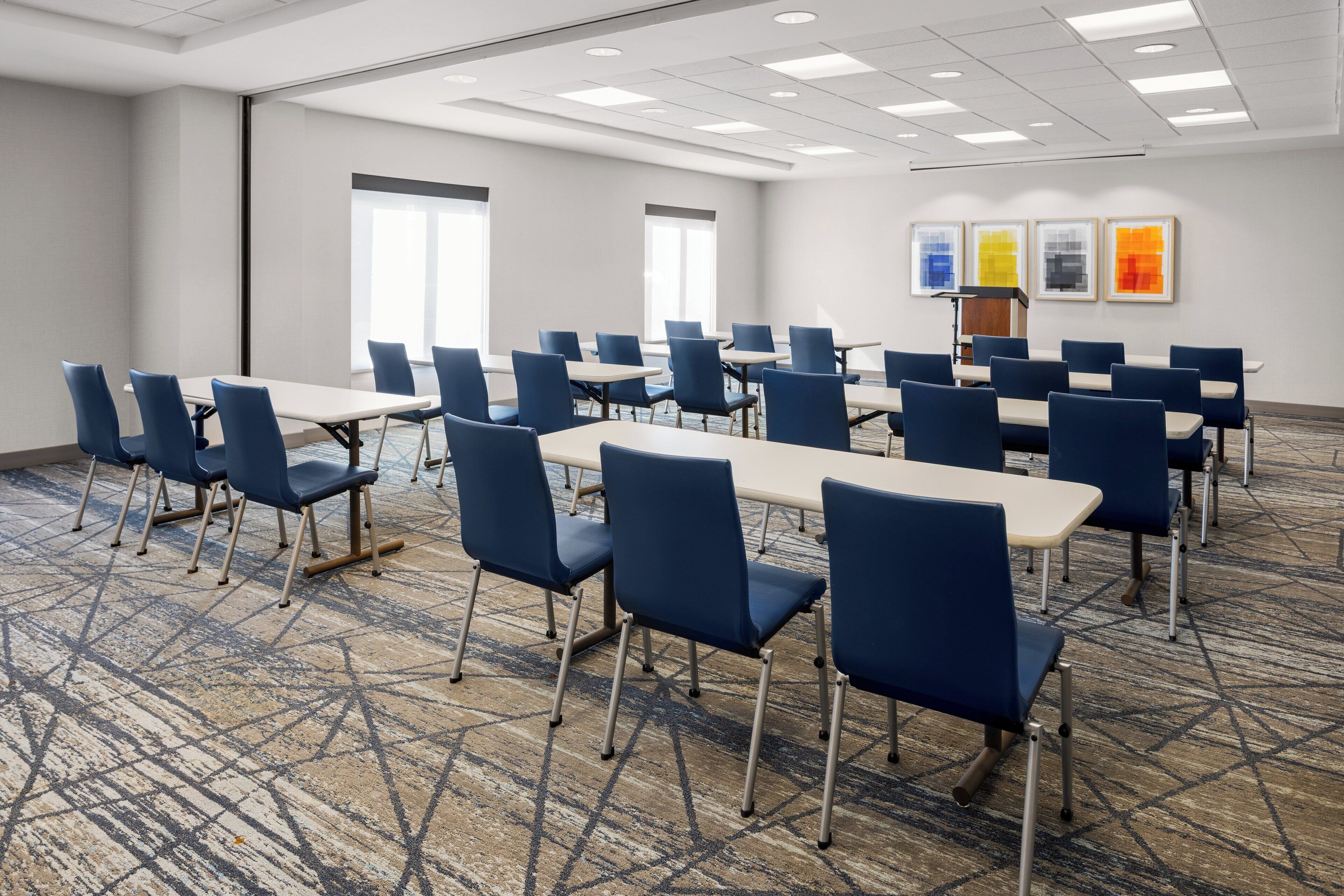 A conference room with a carpeted floor, blue chairs, and a long table.