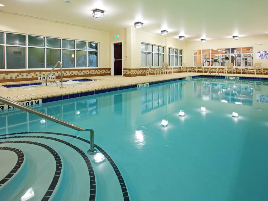 An indoor swimming pool with clear water, marked depth lines, and a tiled edge.