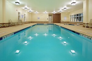 Una amplia piscina interior con marcas claras para carriles, señalización de seguridad y un borde de azulejos.