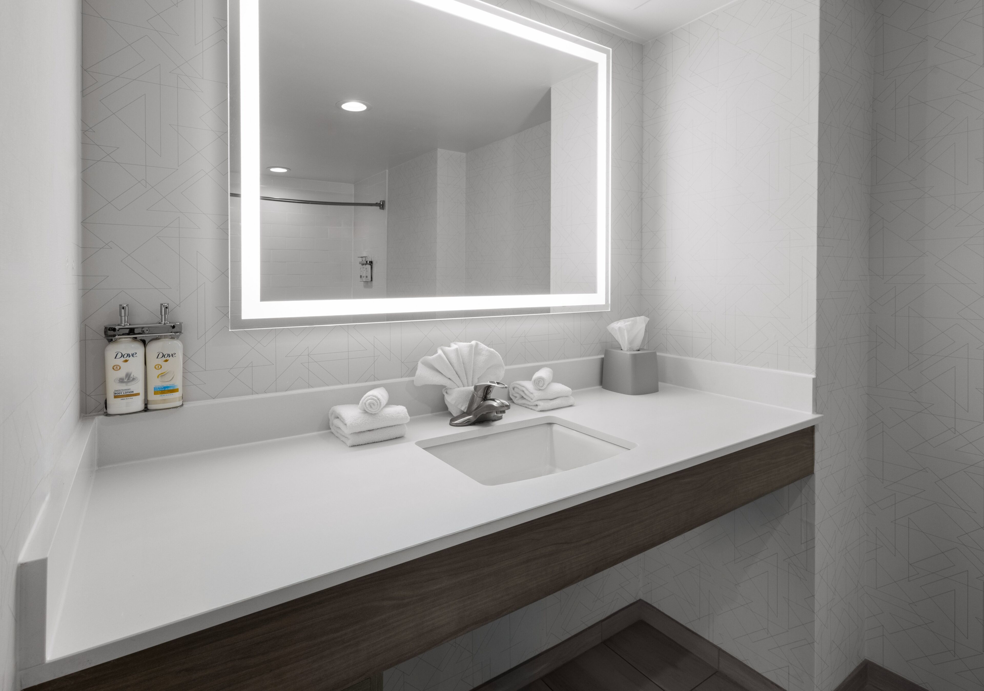 A modern bathroom with a large mirror, a sink, and a towel rack.