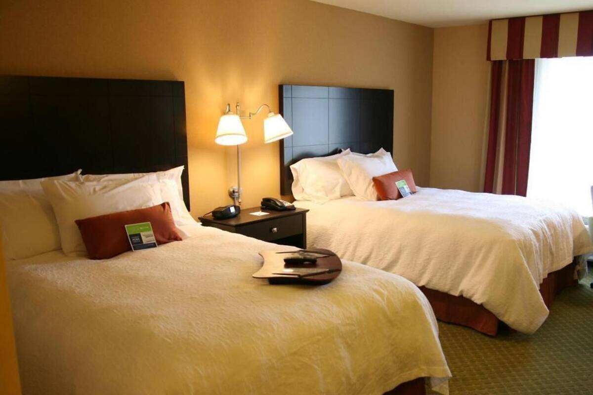 A hotel room with two beds, each with white bedding, a nightstand with a lamp, and a telephone.