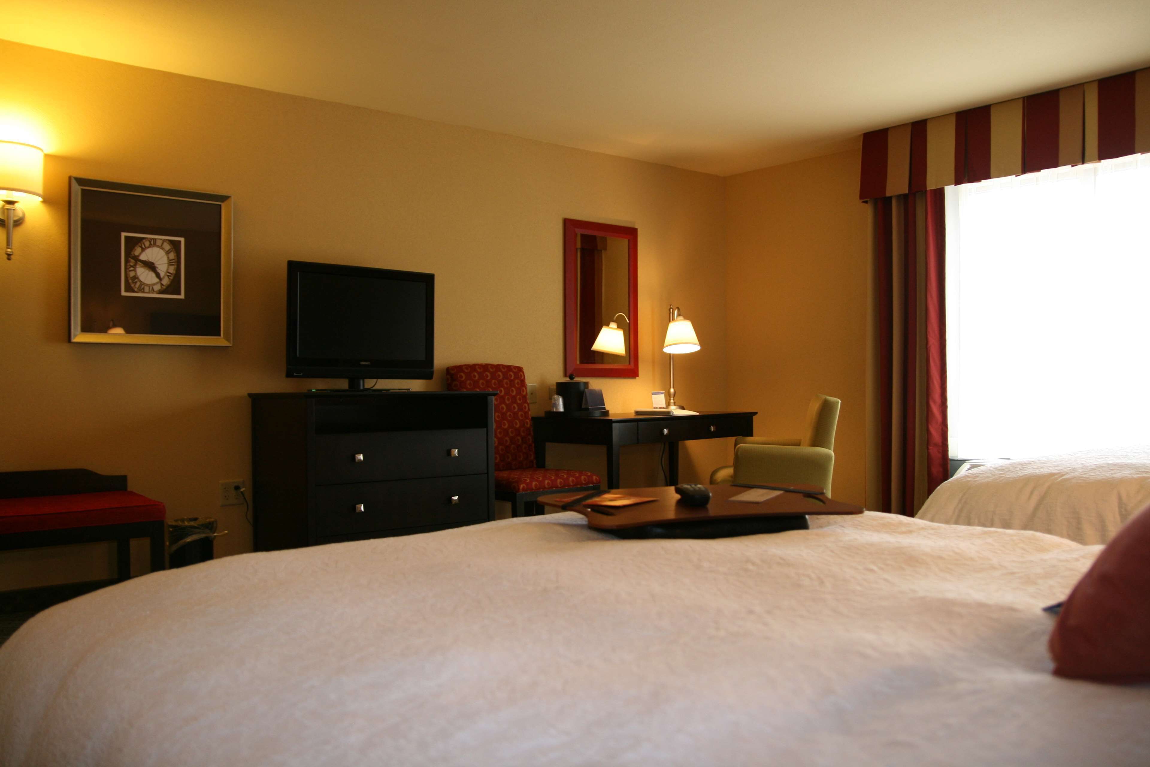 Une chambre d’hôtel équipée d’un lit, d’un bureau, d’une chaise, d’une télévision et d’une lampe.