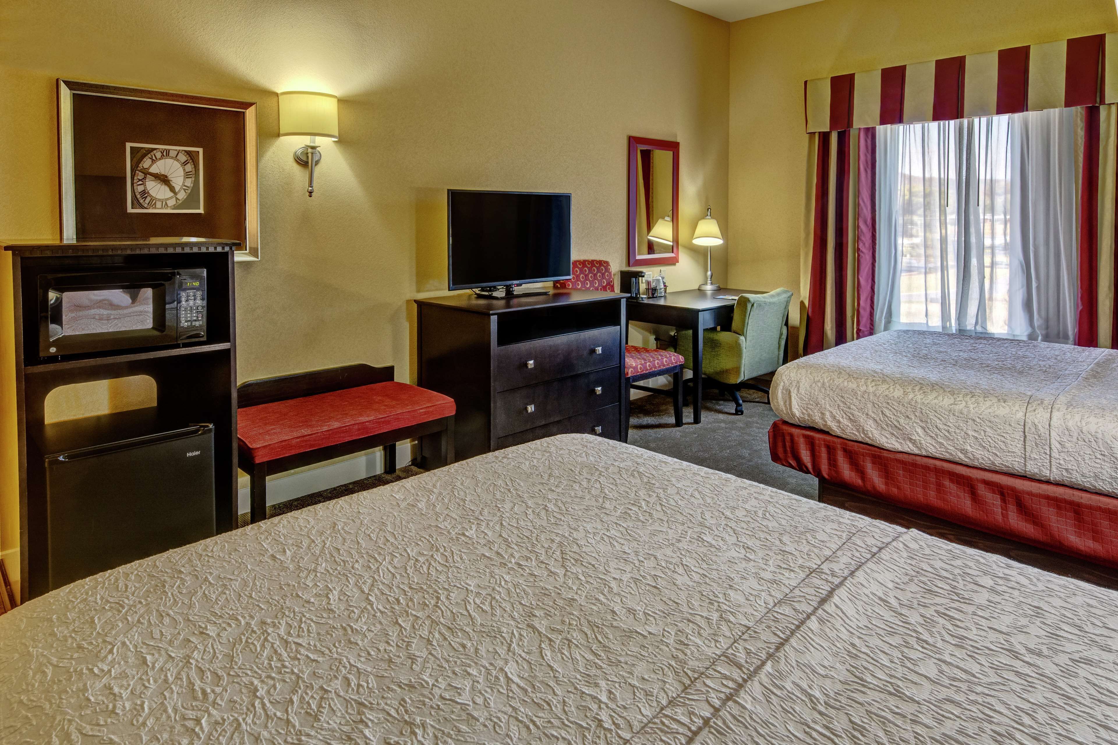 A hotel room with two beds, a desk with a computer, a TV, and a microwave.