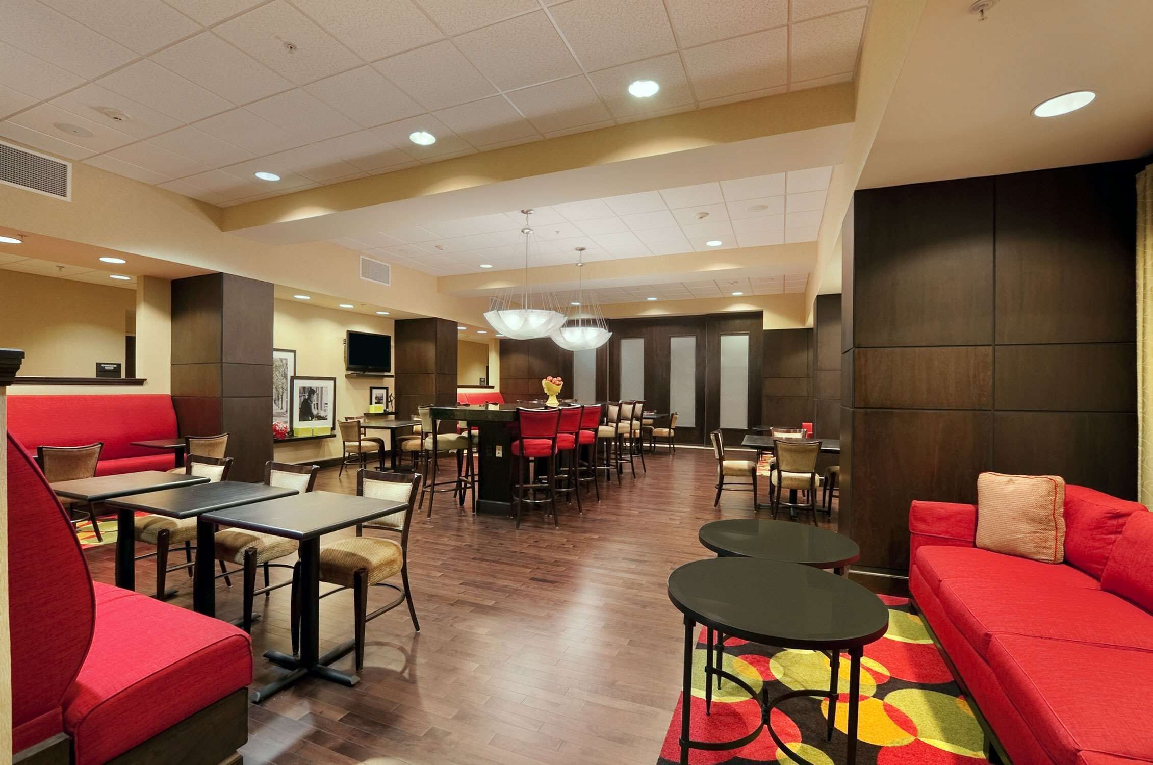 A hotel lobby with red seating, multiple tables, and a chandelier.