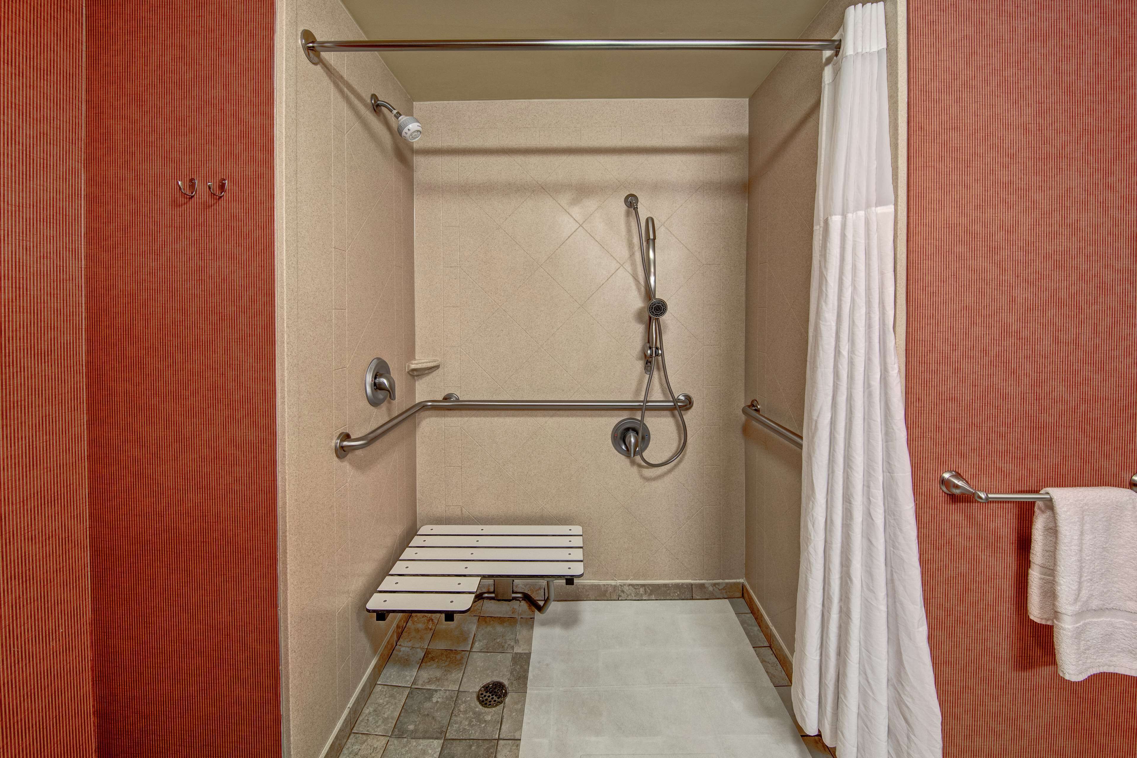 Eine barrierefreie Dusche mit Sitzbank, Haltegriffen und Handtuchhalter.