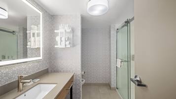 A modern bathroom with a large mirror, a sink, and a glass shower enclosure.