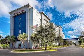 A hotel with a blue and white facade, an American flag, and a parking lot. - Hampton Inn & Suites Ft. Lauderdale West-Sawgrass/Tamarac (Tamarac)