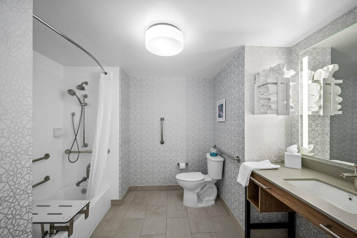 Un baño moderno con ducha, inodoro y tocador con espejo.
