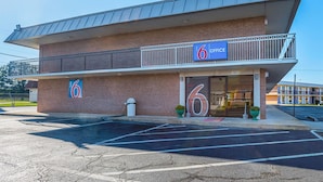 Un motel con un letrero que dice '6 Office', fachada de ladrillo y estacionamiento.