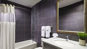 A modern bathroom with a bathtub, toilet, and sink. - American Inn (Downey)